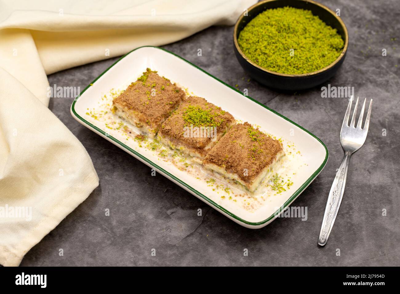 Baklava freddo. Baklava con latte su sfondo scuro. Prelibatezze della cucina mediterranea. Primo piano. Nome locale soguk baklava Foto Stock