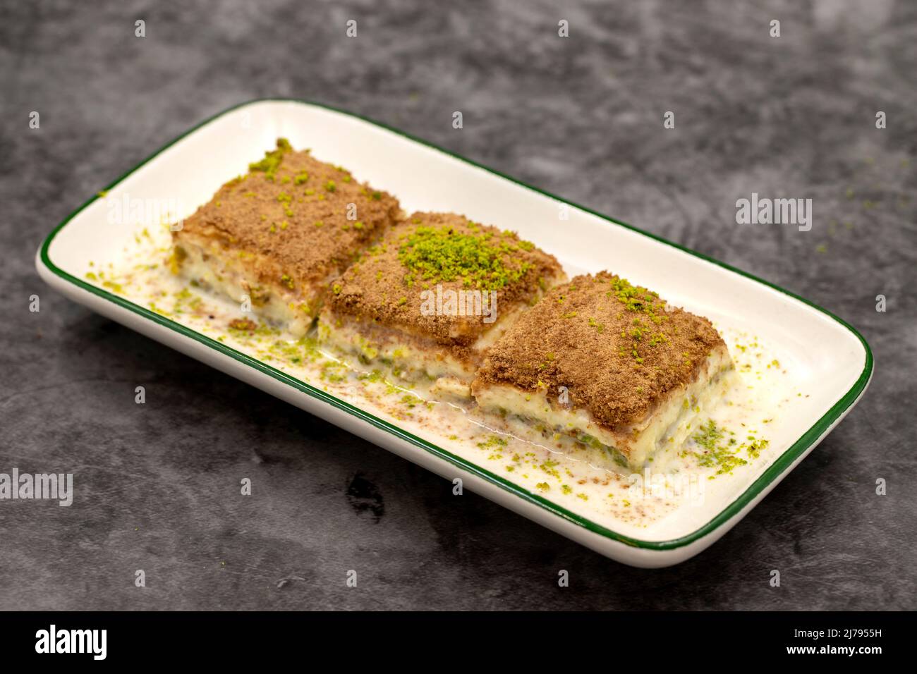 Baklava freddo. Baklava con latte su sfondo scuro. Prelibatezze della cucina mediterranea. Primo piano. Nome locale soguk baklava Foto Stock