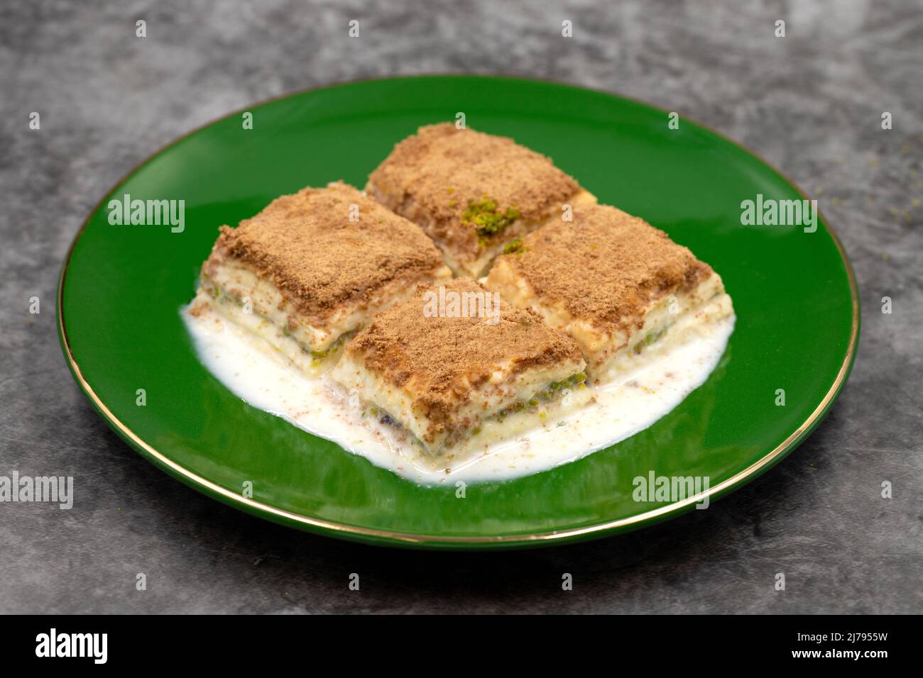 Baklava freddo. Baklava con latte su sfondo scuro. Prelibatezze della cucina mediterranea. Primo piano. Nome locale soguk baklava Foto Stock