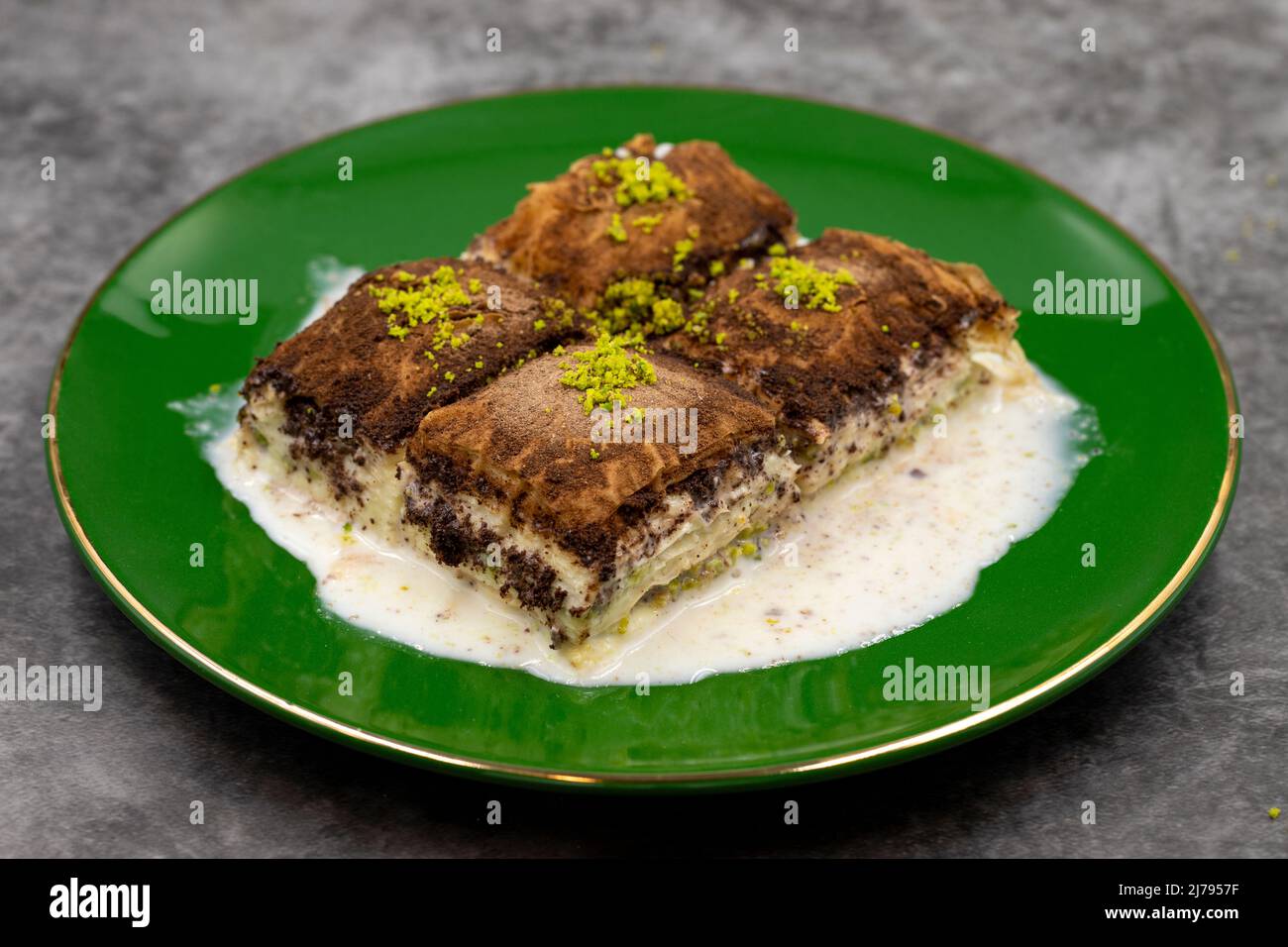 Baklava al cioccolato fondente. Baklava con latte su sfondo scuro. Prelibatezze della cucina mediterranea. Primo piano. Nome locale amaro baklava soguk Foto Stock