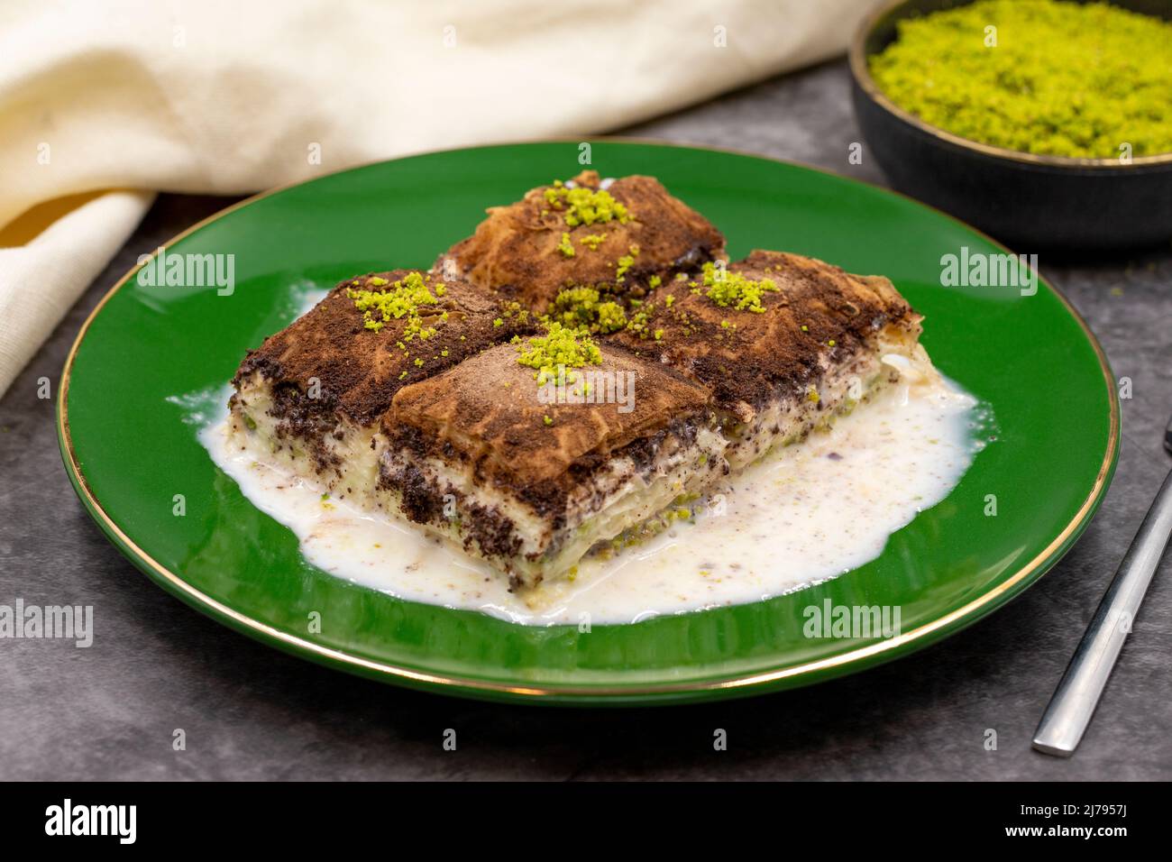 Baklava al cioccolato fondente. Baklava con latte su sfondo scuro. Prelibatezze della cucina mediterranea. Primo piano. Nome locale amaro baklava soguk Foto Stock