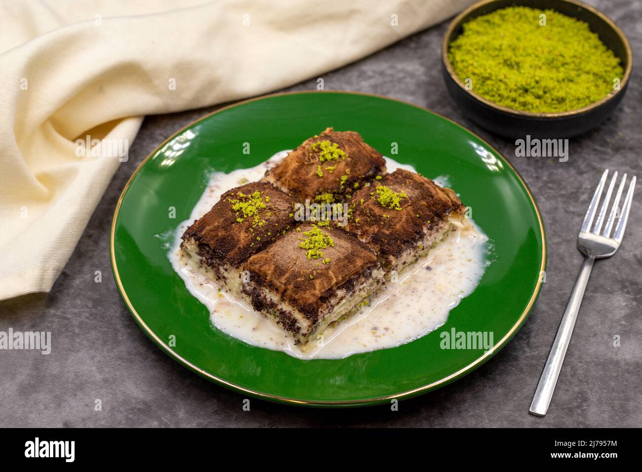 Baklava al cioccolato fondente. Baklava con latte su sfondo scuro. Prelibatezze della cucina mediterranea. Primo piano. Nome locale amaro baklava soguk Foto Stock