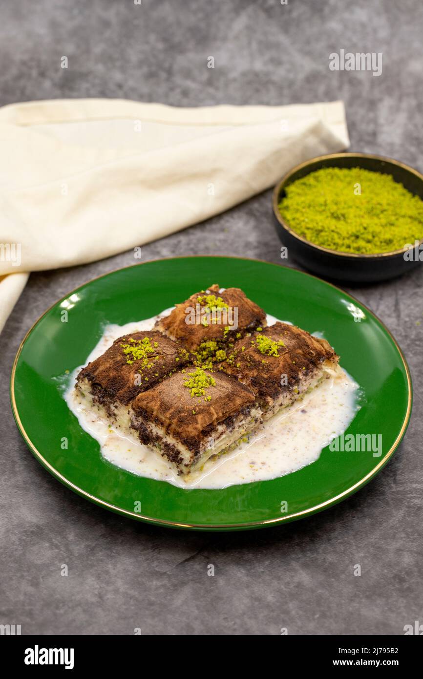 Baklava al cioccolato fondente. Baklava con latte su sfondo scuro. Prelibatezze della cucina mediterranea. Primo piano. Nome locale amaro baklava soguk Foto Stock