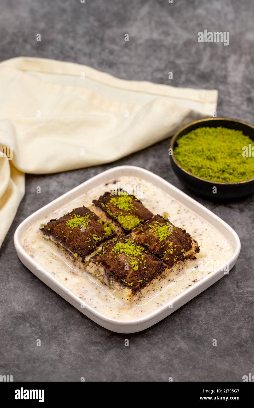 Baklava al cioccolato fondente. Baklava con latte su sfondo scuro. Prelibatezze della cucina mediterranea. Primo piano. Nome locale amaro baklava soguk Foto Stock