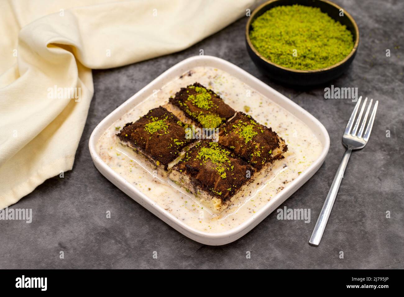 Baklava al cioccolato fondente. Baklava con latte su sfondo scuro. Prelibatezze della cucina mediterranea. Primo piano. Nome locale amaro baklava soguk Foto Stock