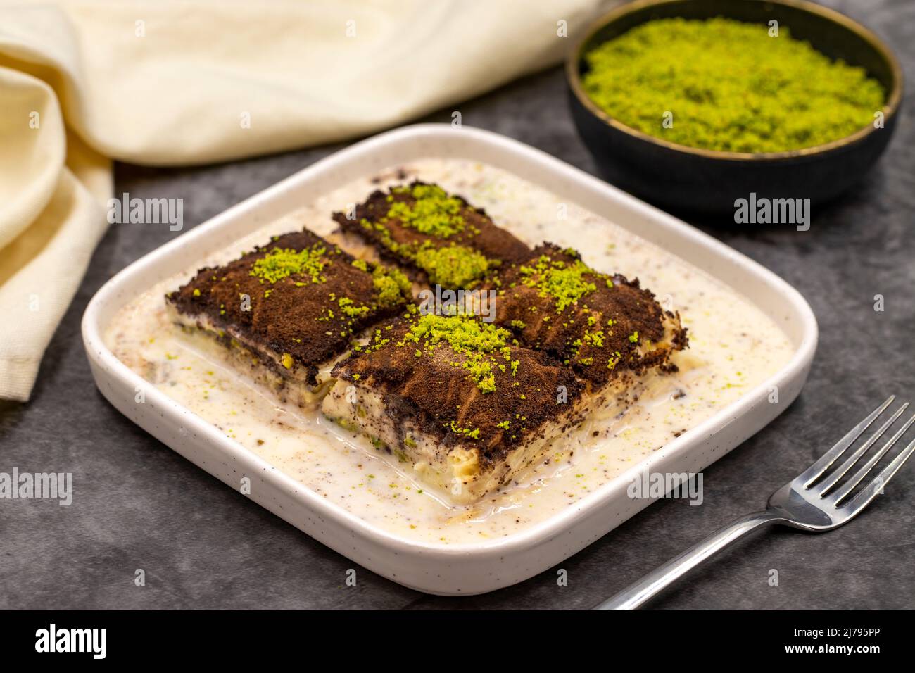 Baklava al cioccolato fondente. Baklava con latte su sfondo scuro. Prelibatezze della cucina mediterranea. Primo piano. Nome locale amaro baklava soguk Foto Stock