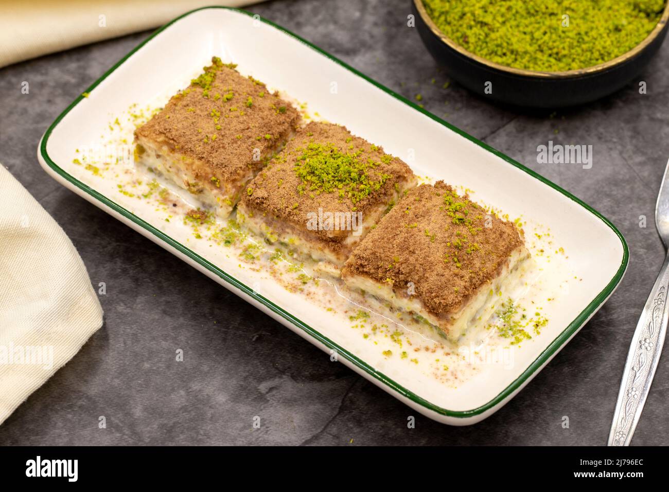 Baklava freddo. Baklava con latte su sfondo scuro. Prelibatezze della cucina mediterranea. Primo piano. Nome locale soguk baklava Foto Stock