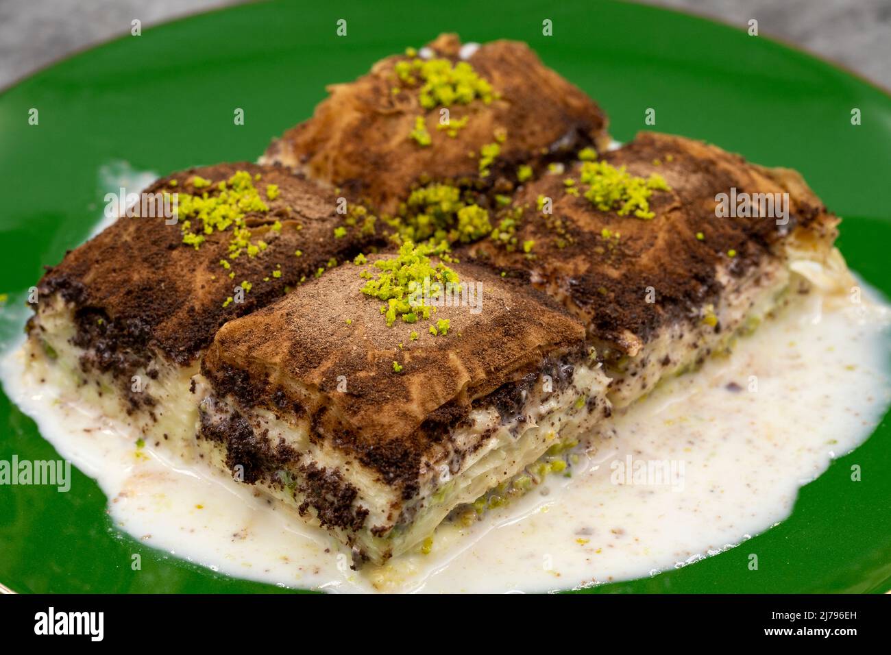 Baklava al cioccolato fondente. Baklava con latte su sfondo scuro. Prelibatezze della cucina mediterranea. Primo piano. Nome locale amaro baklava soguk Foto Stock
