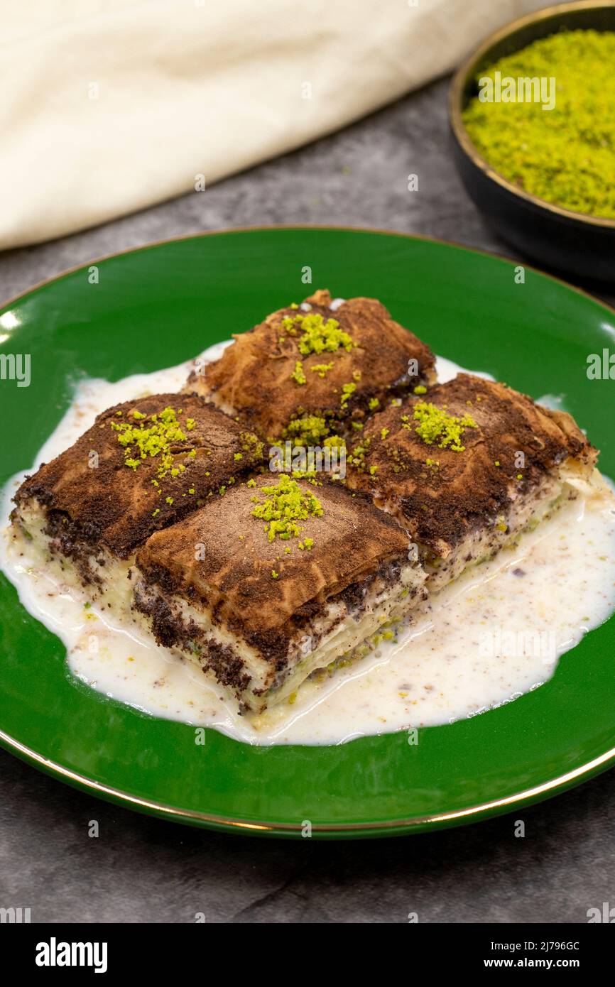 Baklava al cioccolato fondente. Baklava con latte su sfondo scuro. Prelibatezze della cucina mediterranea. Primo piano. Nome locale amaro baklava soguk Foto Stock