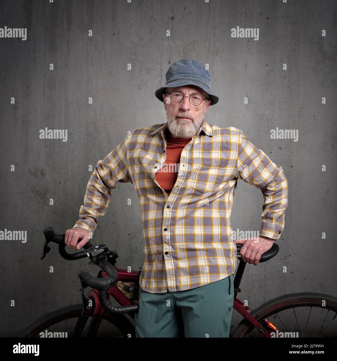 ritratto casuale di ciclista maschile senior con una ghiaia o bicicletta da turismo contro una parete di cemento grunge Foto Stock