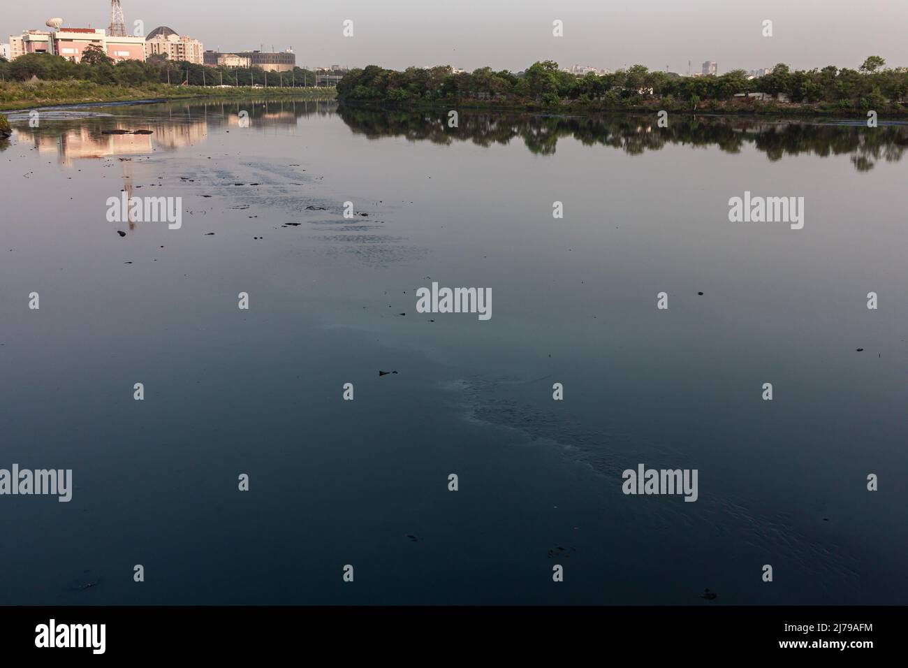 Vista panoramica delle rive del fiume Coovum che scorre attraverso il cuore della città di Chennai, Tamil Nadu, India. Messa a fuoco impostata sull'acqua di fiume Foto Stock