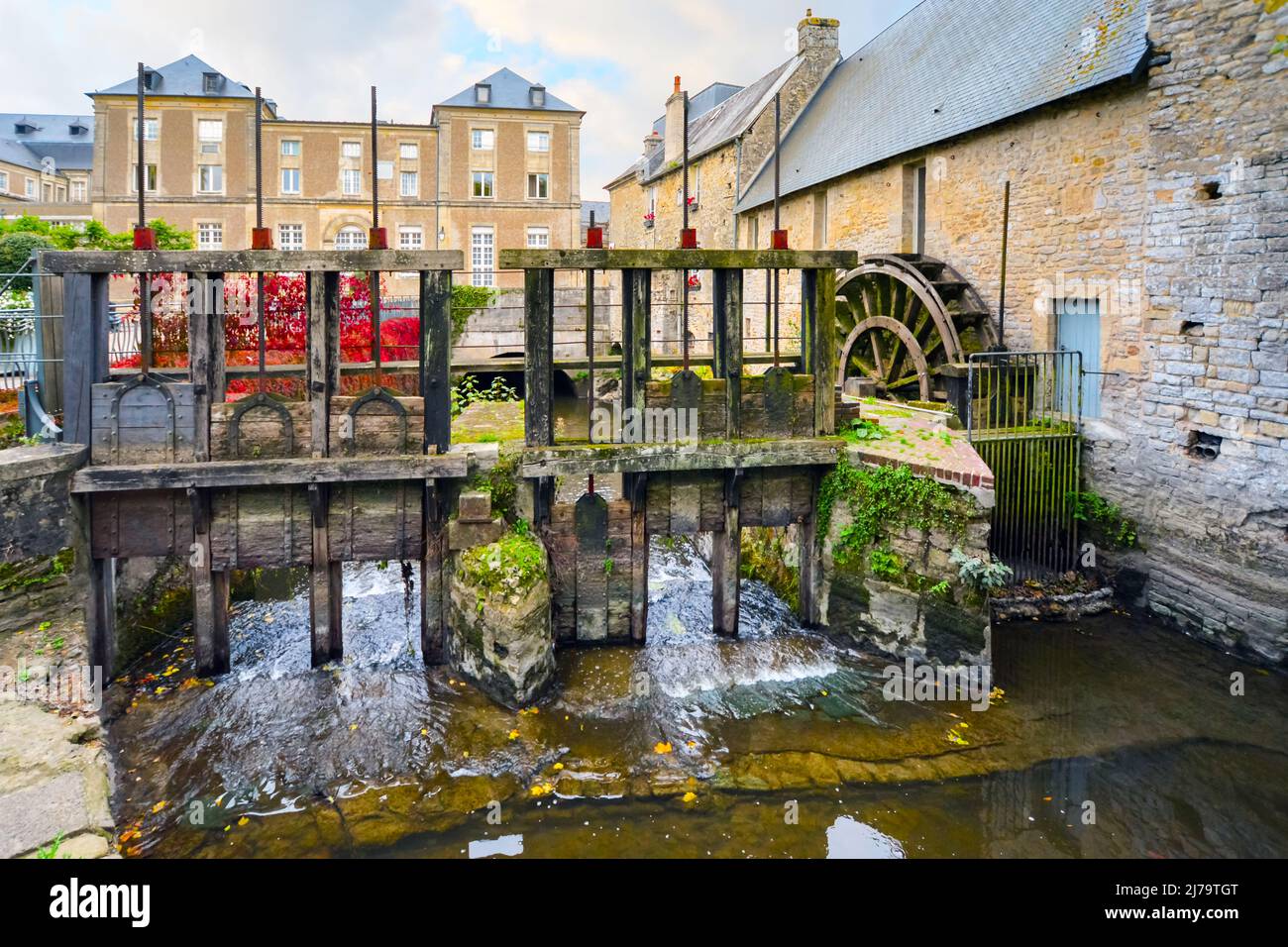 Il mulino ad acqua sul fiume Aure nella città medievale di Bayeux sulla costa della Normandia in Francia con inizio autunno colori Foto Stock