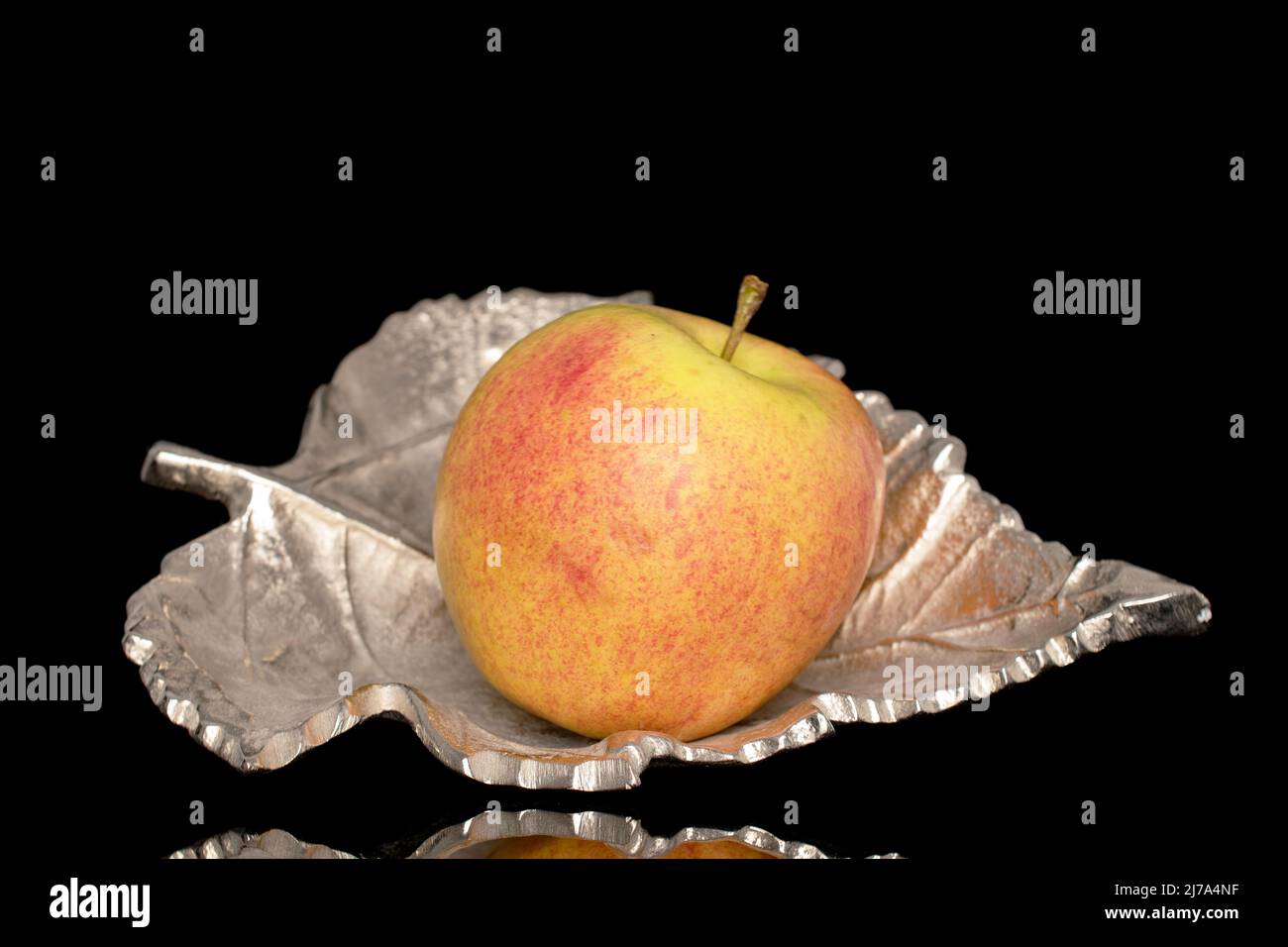 Una succulenta mela biologica in una ciotola di metallo, primo piano, isolata su sfondo nero. Foto Stock