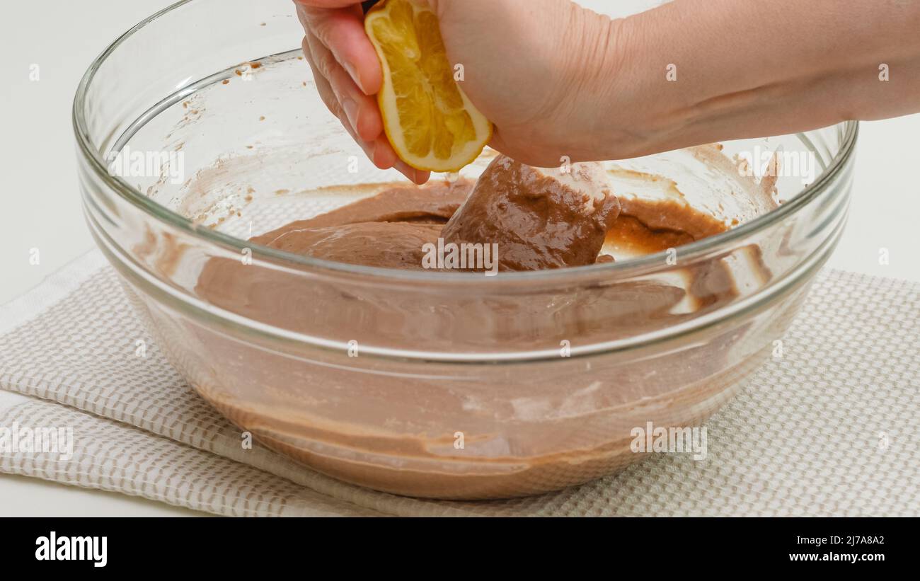 Ricetta torta al cioccolato. Mescolare l'impasto per torte in un recipiente di vetro e spremere il succo di limone chiudere il processo di cottura Foto Stock