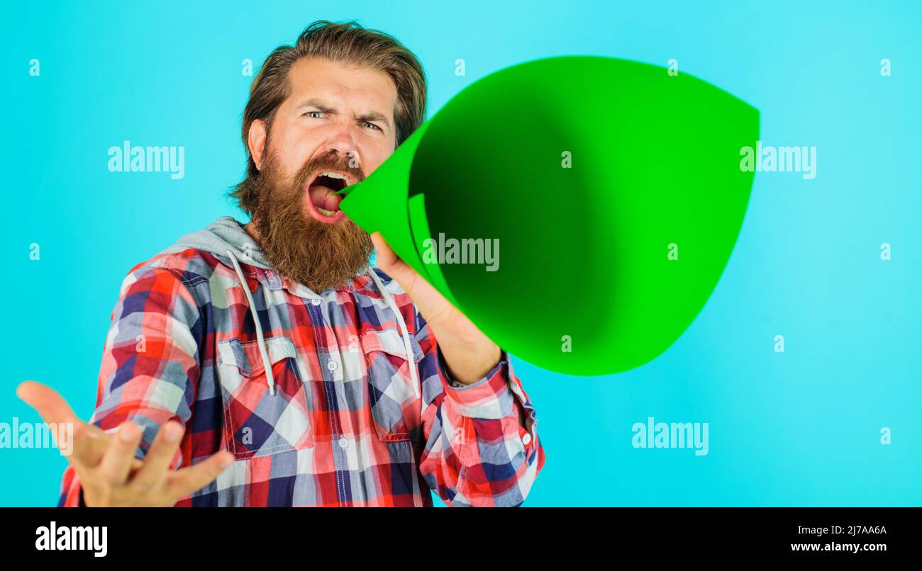 L'uomo grida nell'altoparlante. Ragazzo bearded urlando nel corno di corno. Hipster con megafono. Sconto, vendita. Foto Stock