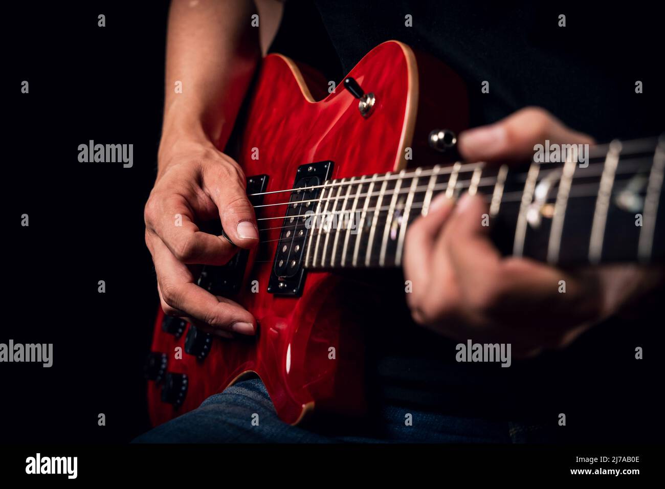 Primo piano di un uomo che suona una chitarra elettrica rossa lucida Foto Stock