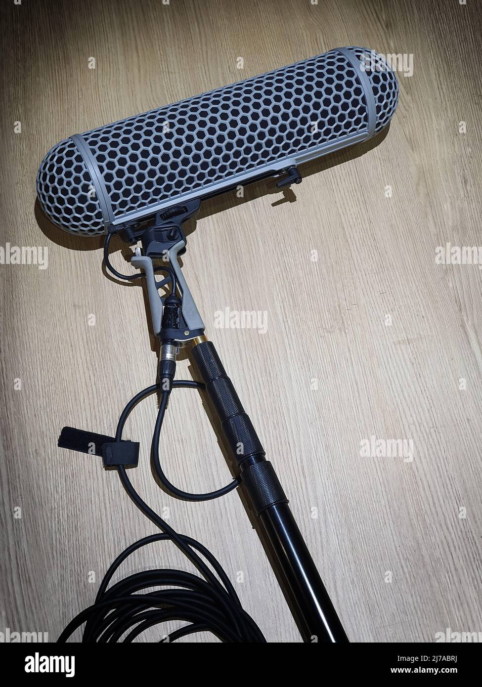 Microfono ad asta o microfono ambientale per la registrazione del suono  nella produzione video. I microfoni con asta portamicrofono si appoggiano  sul tavolo in legno dopo l'uso nelle riprese di film online.