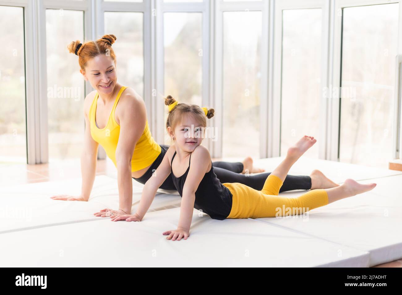 Giovane madre che insegna a sua figlia yoga posa. Cane rivolto verso l'alto Foto Stock