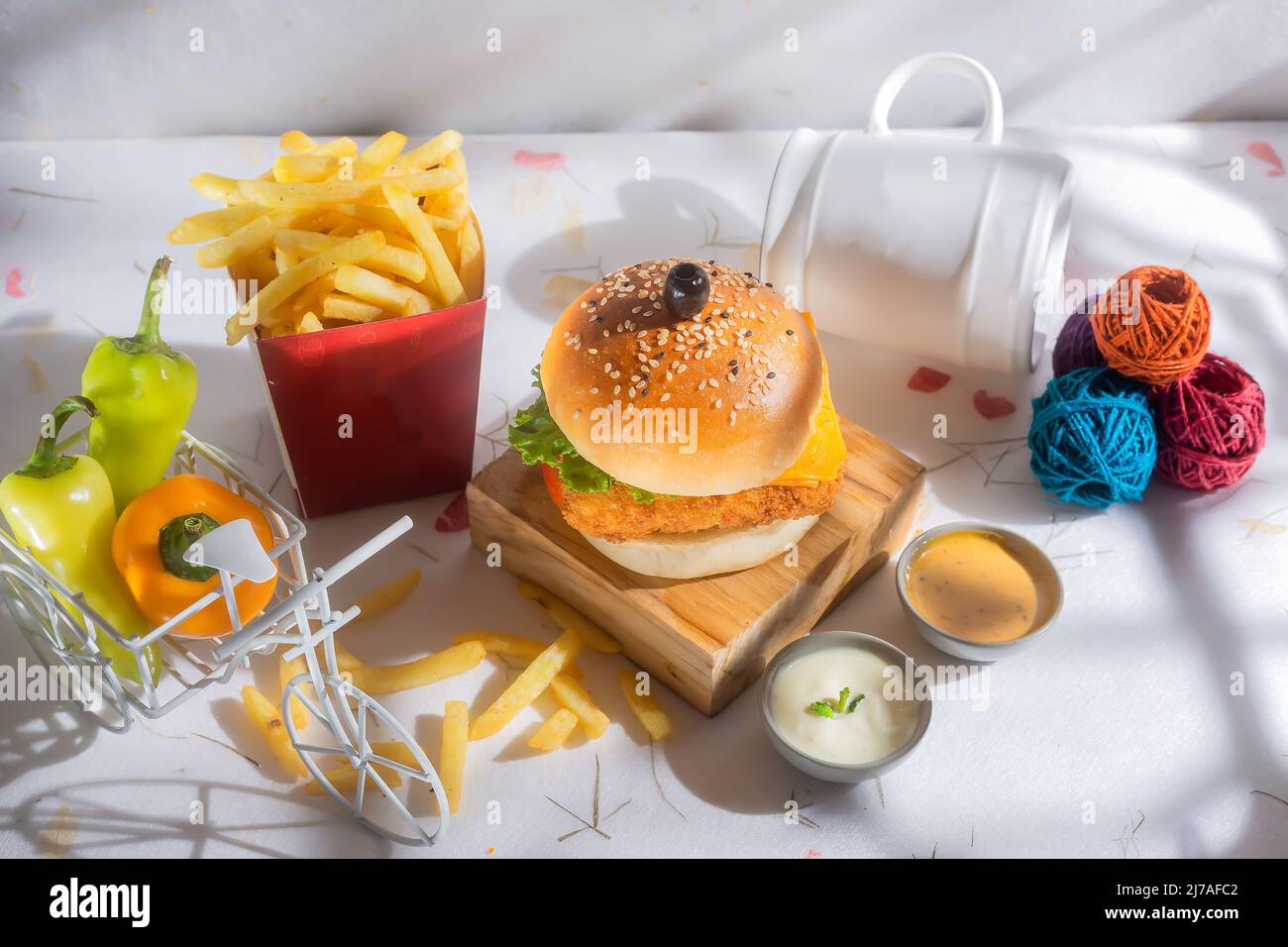 Fish Burger con patatine fritte di pomodoro, e peperoncino verde isolato su tavola di legno vista laterale di fast food americano Foto Stock