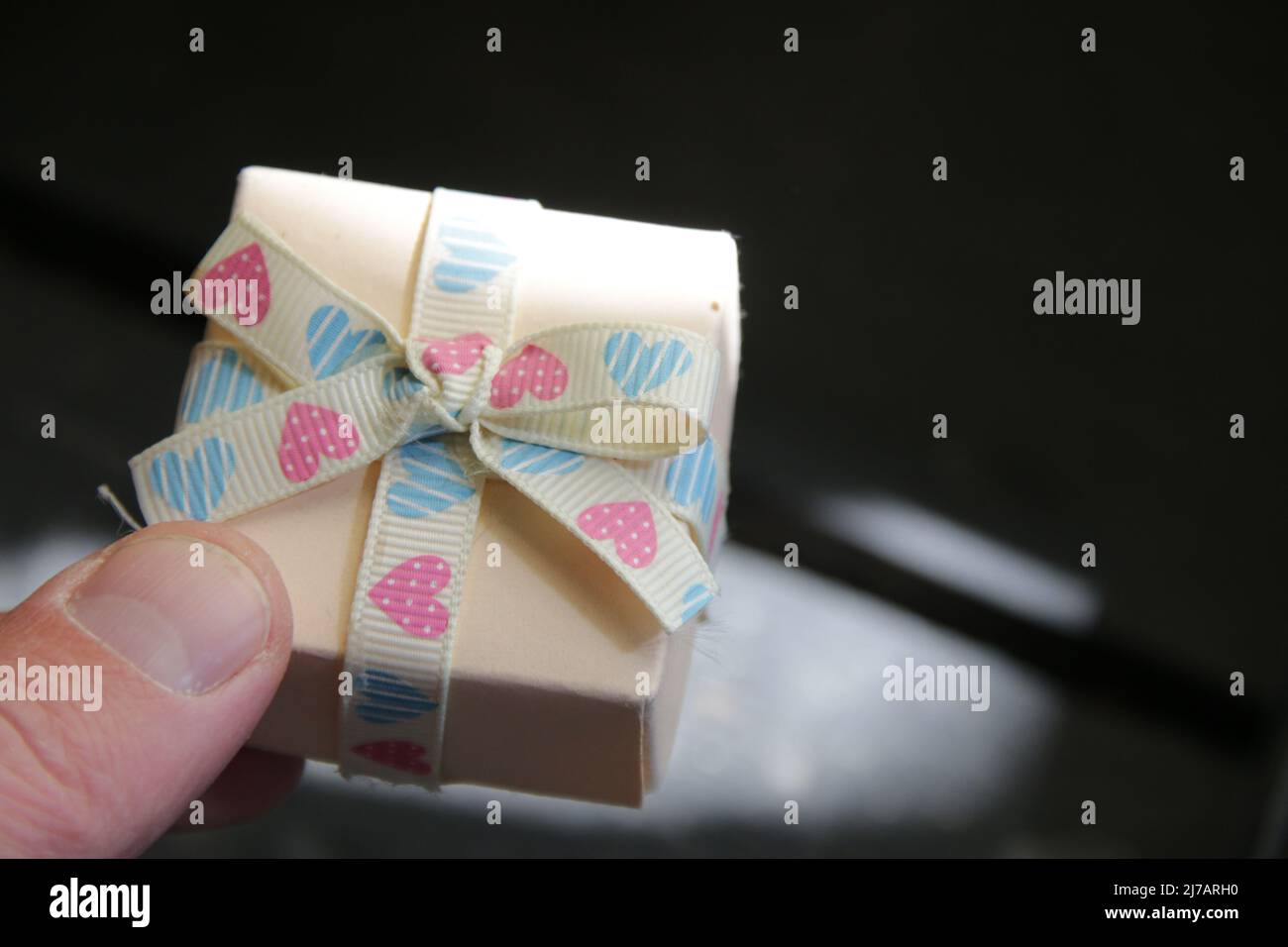 Una mano dell'uomo tiene una scatola del regalo con un nastro. Foto Stock