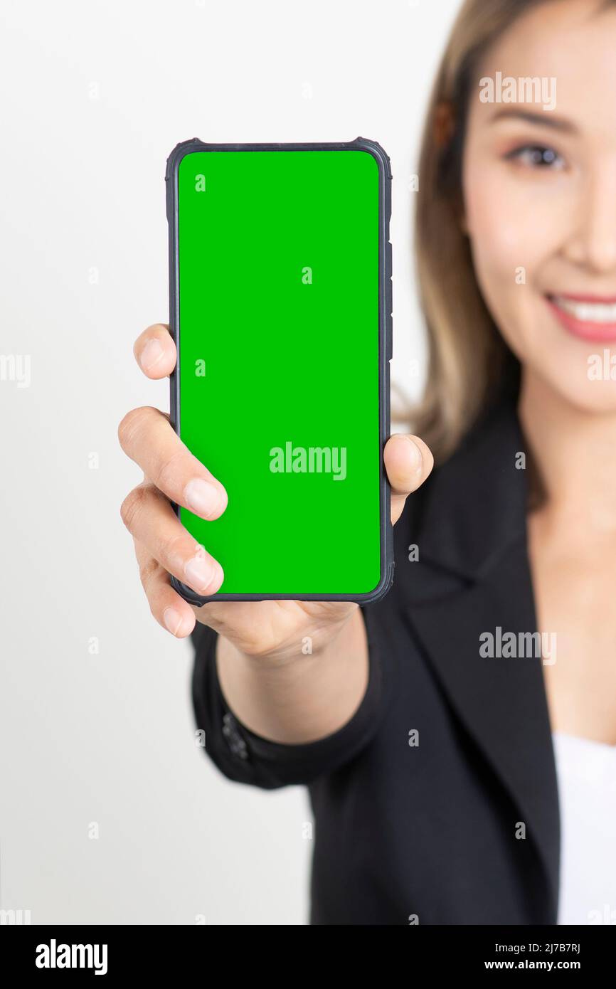 Donna da lavoro in abito nero che mostra lo schermo verde sul display dello smartphone su sfondo bianco. Metà faccia di donna d'affari che tiene lo smartphone con gr Foto Stock