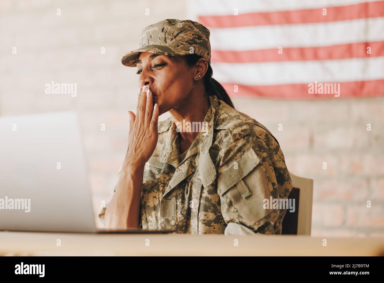 La soldato americano soffia un bacio mentre chiacchiava con la famiglia su un computer portatile. Servizio patriottico che comunica con i suoi cari whil Foto Stock