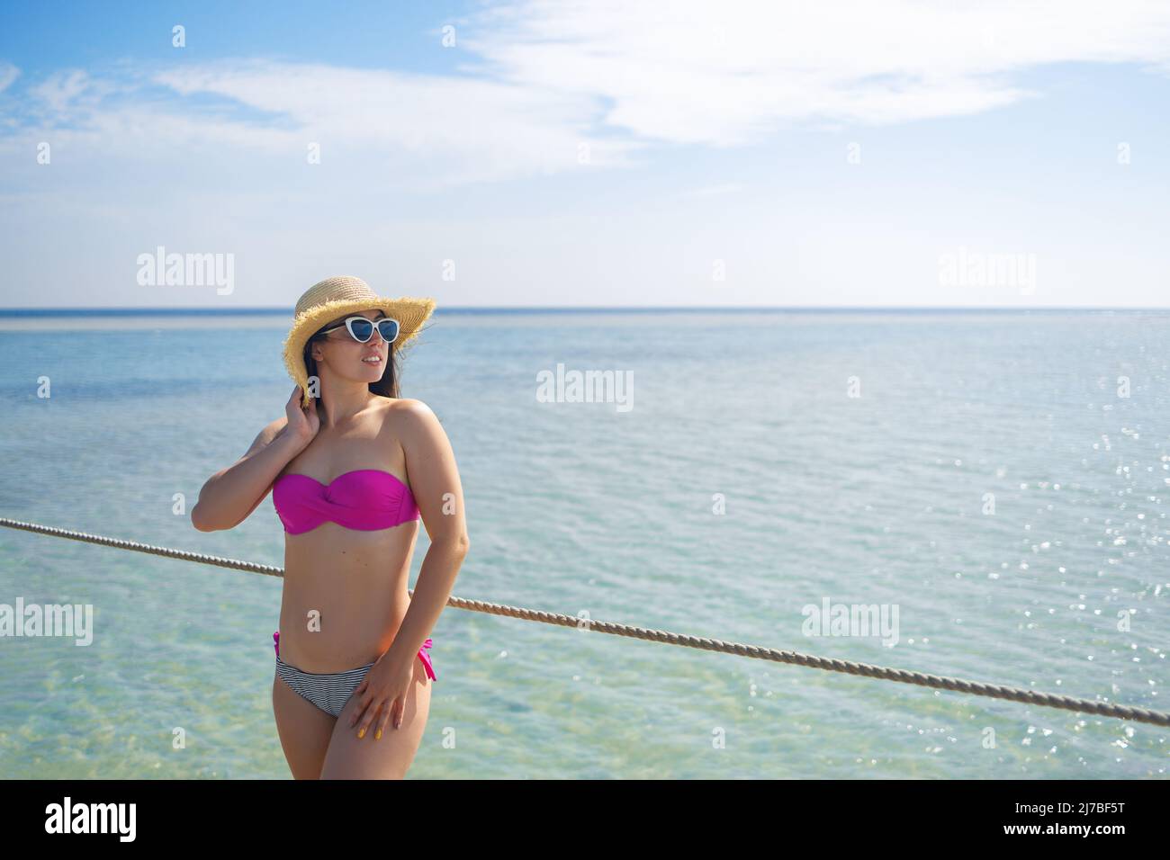 giovane donna sorridente in cappello di paglia sul pontile Foto Stock