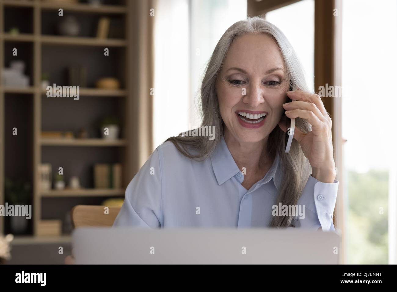 Felice 50s signora di affari che parla sul telefono mobile al portatile Foto Stock