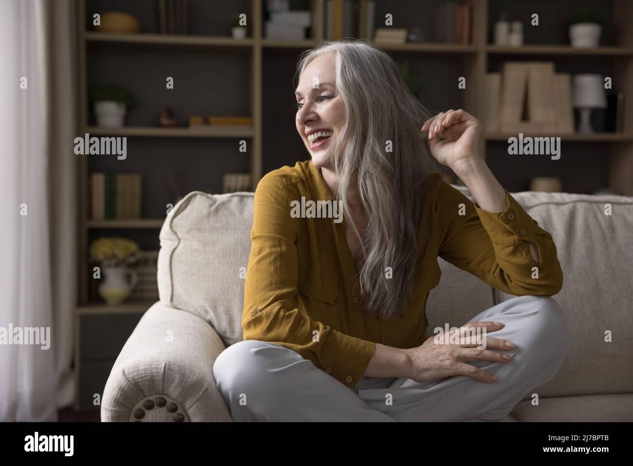 Allegro maturo 50s donna seduta sul divano a casa Foto Stock