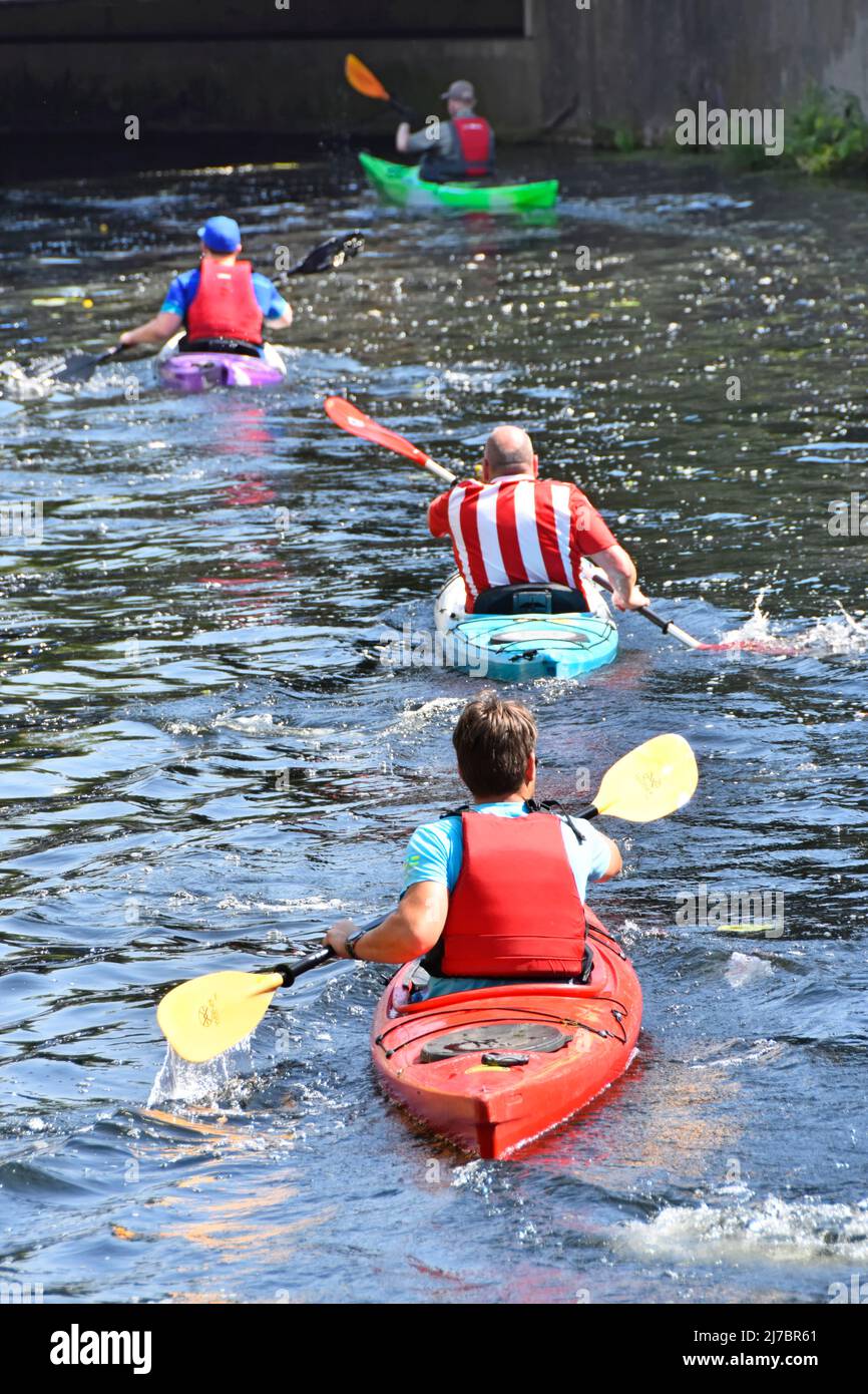 Vista posteriore di quattro ragazzi pagaiare Kayaks lungo il fiume può in una giornata estiva al sole che si avvicina a un ponte stradale Chelmsford centro città Essex Inghilterra Regno Unito Foto Stock