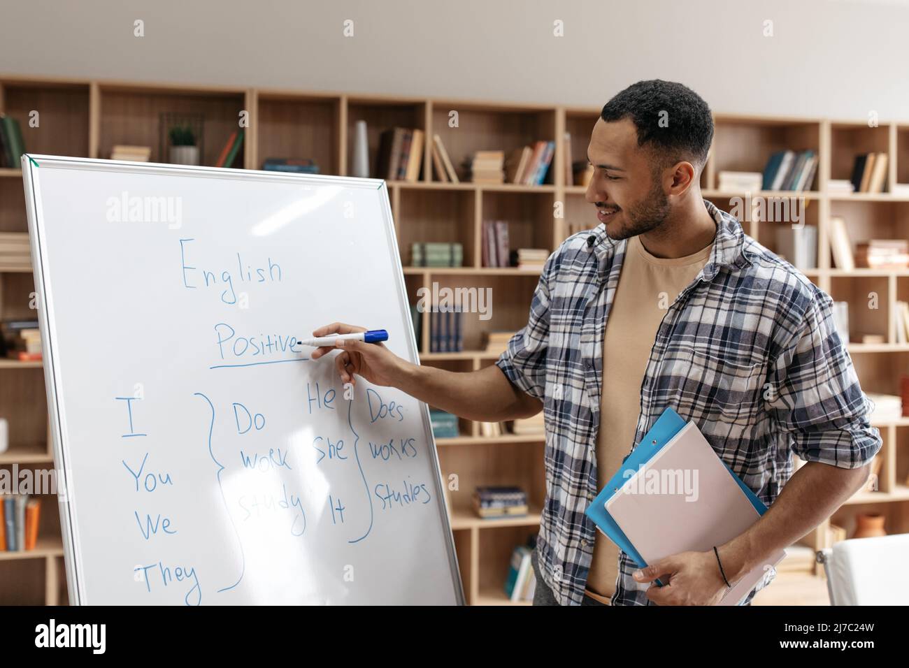 Cheerful maschio arabo tutor insegnamento della lingua inglese, spiegando nuovo tema agli studenti Foto Stock