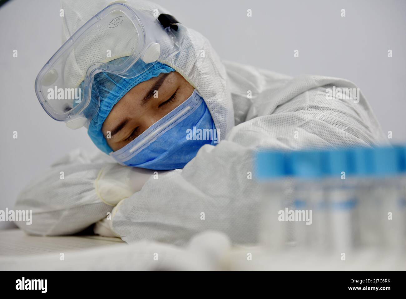 ZHANGJIAKOU, CINA - 11 FEBBRAIO 2020 - Un'infermiera si addormenta sul tavolo senza togliere i suoi indumenti protettivi dopo il suo turno di emergenza 120 Foto Stock