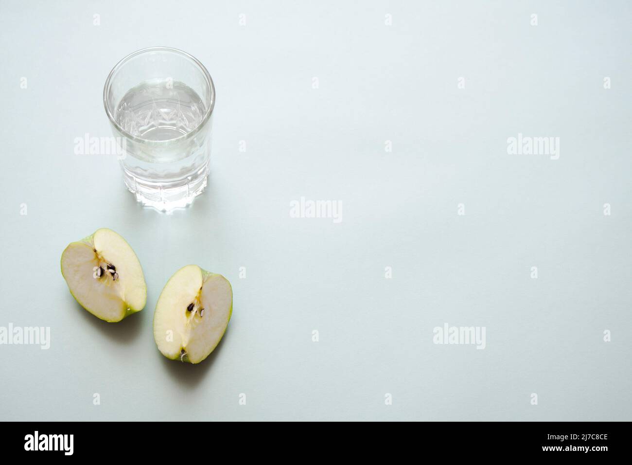 Pezzi di mela e un bicchiere di acqua fredda con spazio libero per la pasta di copia. Stile di vita sano e dieta concetto di vita morta. Foto Stock