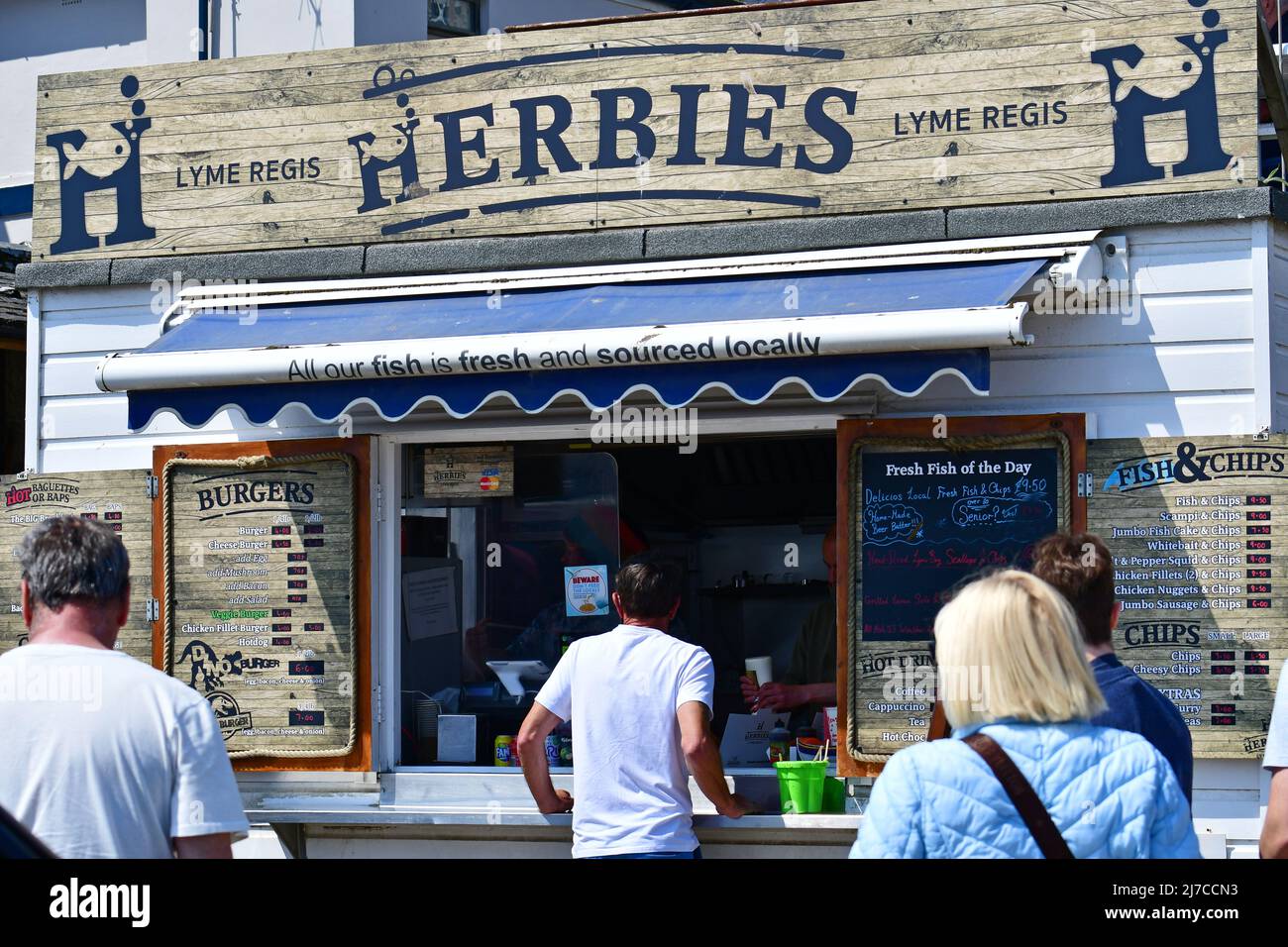 Lyme Regis, Devon, Regno Unito. 8th maggio 2022. Meteo Regno Unito. In un pomeriggio molto caldo a Lyme Regis in Devon sulla splendida costa di negozi e ristoranti lungo la passeggiata di fronte è uno dei pochi pesci e patatine serviti da un furgone sul Cobb. Herbies serve favolose patatine di pesce pescate localmente e capesante da morire. Foto di credito Robert Timoney/AlamyLiveNews Foto Stock