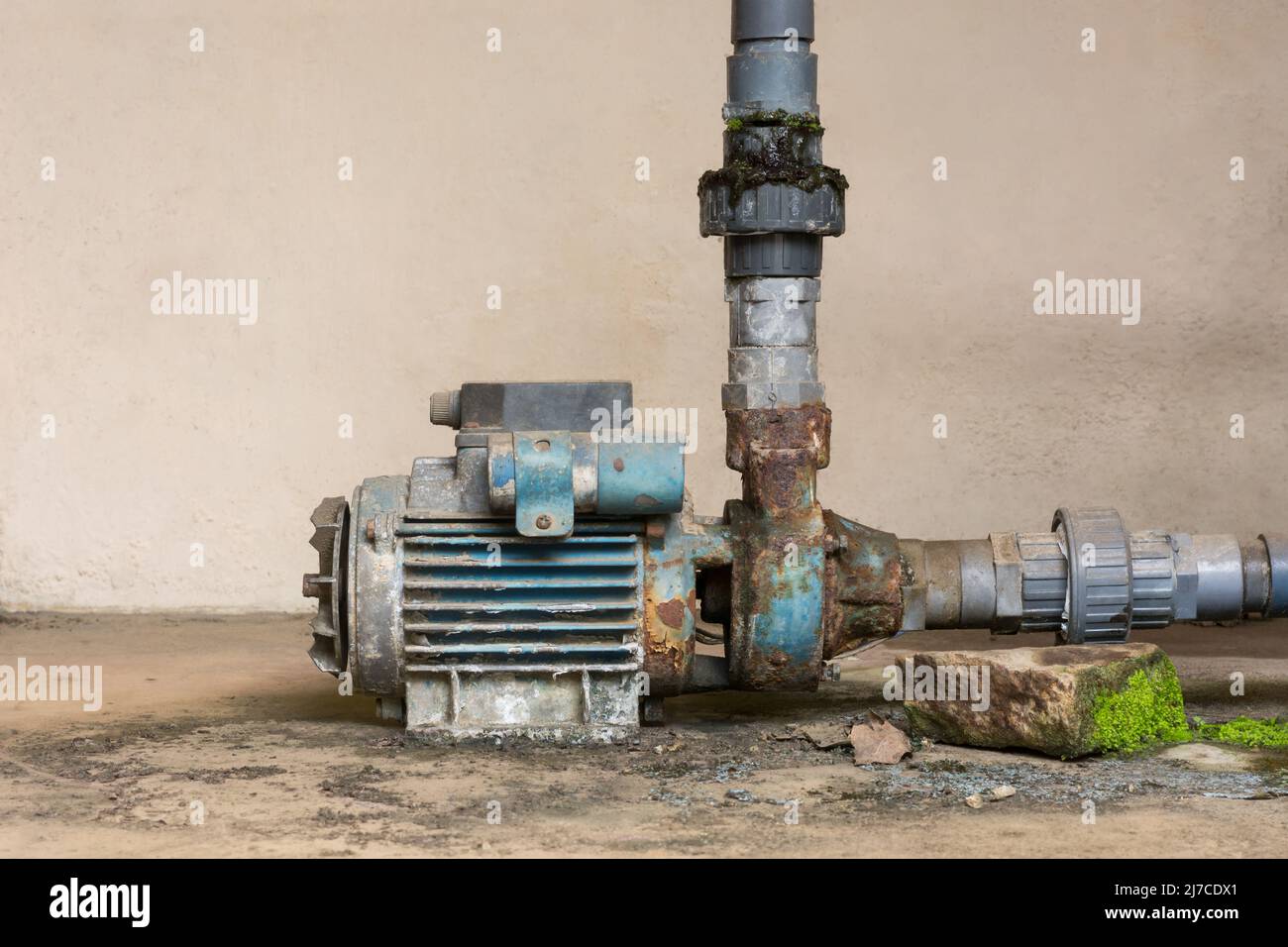 vecchia pompa dell'acqua elettrica arrugginita con tubazioni di alimentazione dell'acqua in pvc, spazio di copia Foto Stock