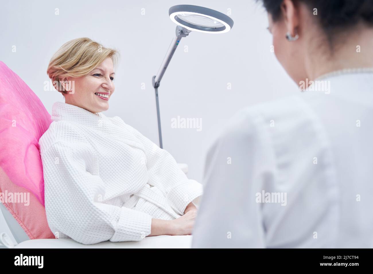 Donna adulta allegra seduta in sedia nel salone di bellezza Foto Stock