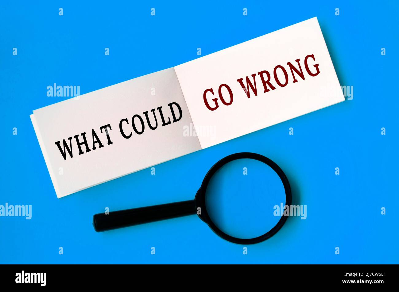 Che cosa potrebbe andare il testo errato sul blocco note con la lente di ingrandimento su sfondo blu. Concetto di scoperta dei fatti Foto Stock