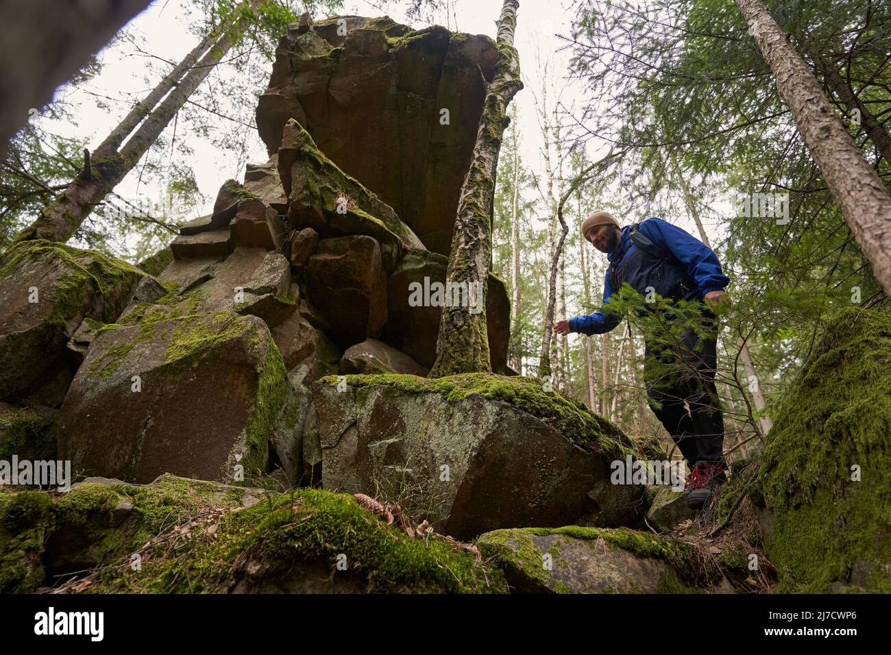 Maschio scendendo da pietre mosy durante l'escursione Foto Stock