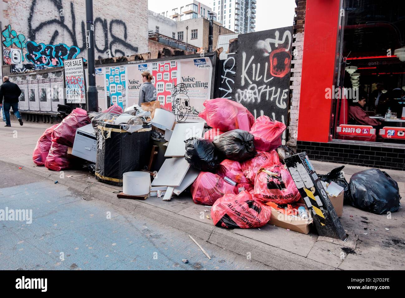 Sacchi di rifiuti commerciali e altri rifiuti impilati sul lato della strada. Whitechapel, Londra, Regno Unito. Foto Stock