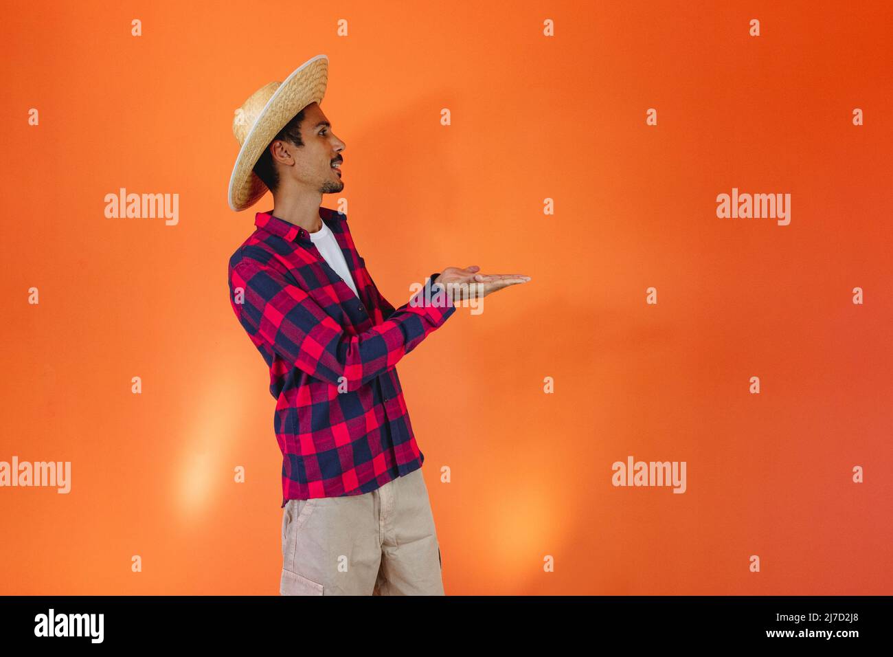Uomo nero che indossa abiti tradizionali per Festa Junina isolato su sfondo arancione Foto Stock