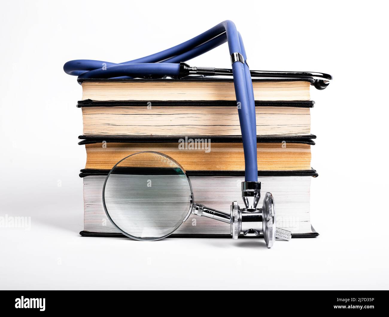 I libri si impilano con stetoscopio e lente d'ingrandimento. Ricerca e apprendimento di dati medici, preparazione all'esame, conduzione della ricerca in ambito medico. Foto di alta qualità Foto Stock