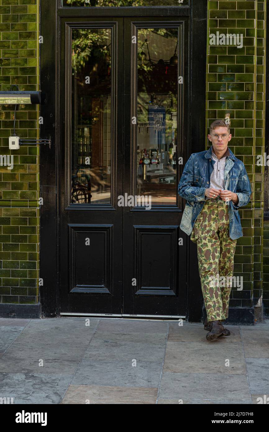 Uomo elegante che indossa pantaloni camouflage fuori pub laterale Foto Stock
