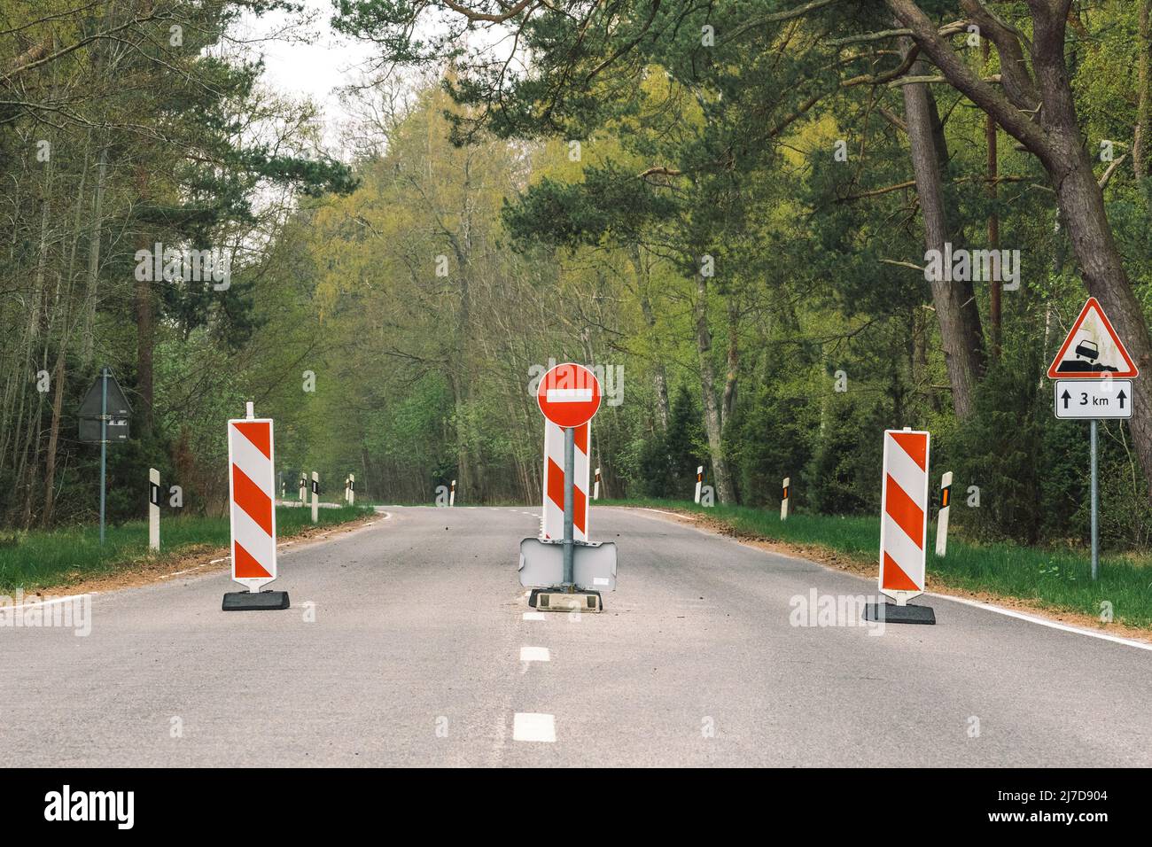 Restrizioni di viaggio, strada chiusa, chiusura delle frontiere, frontiere chiuse, strada vuota e foresta con segnale di stop e barriere Foto Stock
