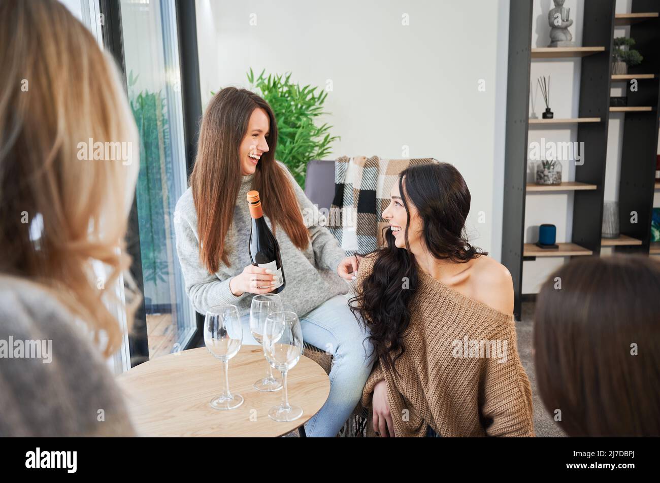 Le giovani donne che si divertiscono nei fine settimana invernali all'interno di una caserma contemporanea. Quattro ragazze che si divertono e bevono vino. Foto Stock