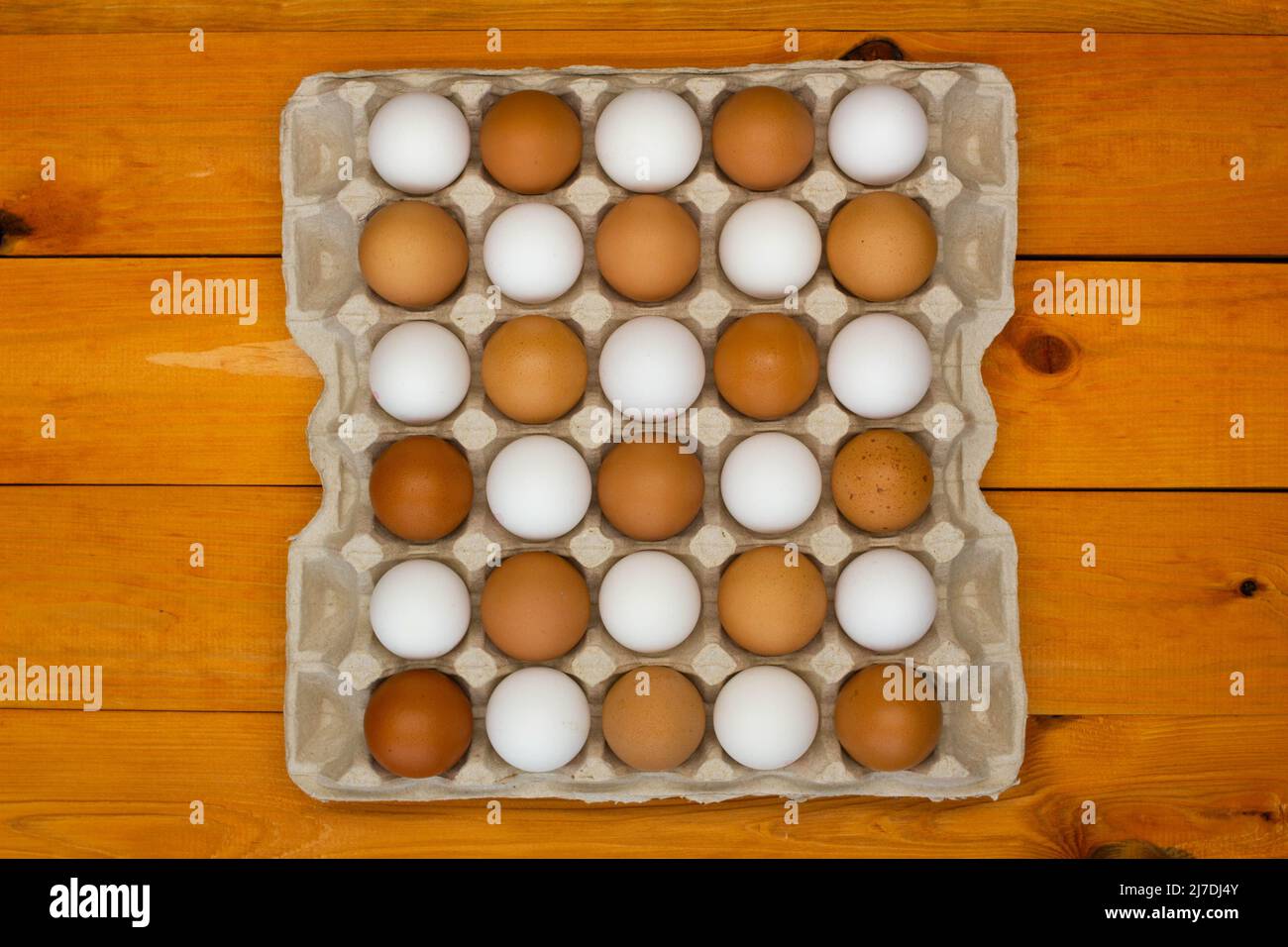 Uova di pollo in un pacchetto sul tavolo. Far rosolare e rosolare le uova di pollo nel vassoio con un motivo a scacchiera. Prodotti ecologici naturali. Fresco Foto Stock