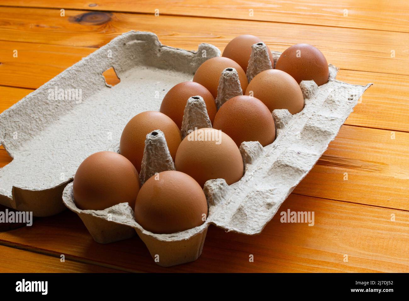 Uova di pollo in un pacchetto sul tavolo. Rosolare le uova di pollo in una scatola di carta riciclata su uno sfondo di legno. Prodotti naturali ecologici e sani. Molto Foto Stock