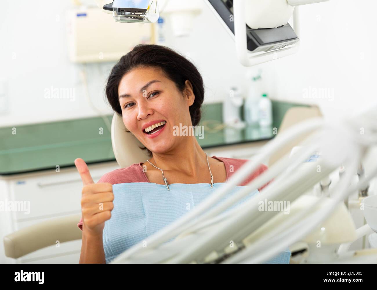 Paziente femminile che mostra il pollice in su dopo il trattamento dentale in clinica Foto Stock