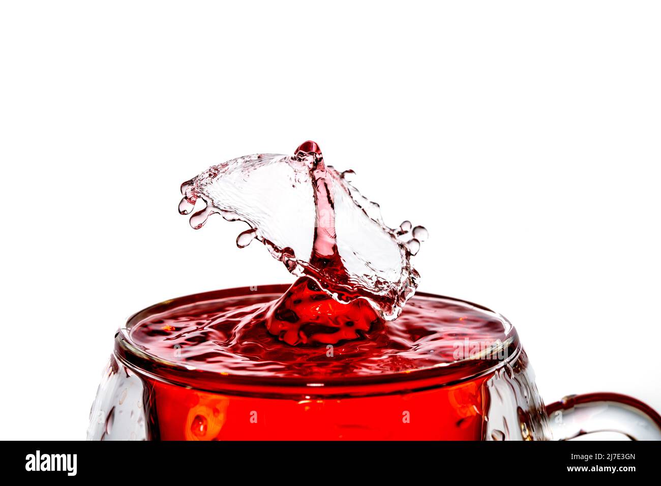 Scatto macro di una caduta collisione in un bicchiere di acqua rossa. Foto Stock