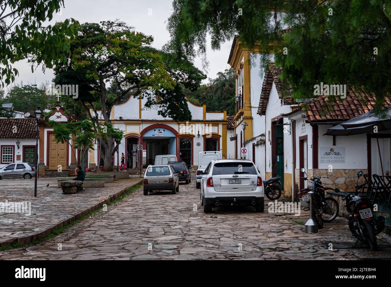 Traffico locale passando per via Silvio Vasconcelos tra edifici coloniali e piazza Largo das Forras nel centro storico di Tiradentes. Foto Stock