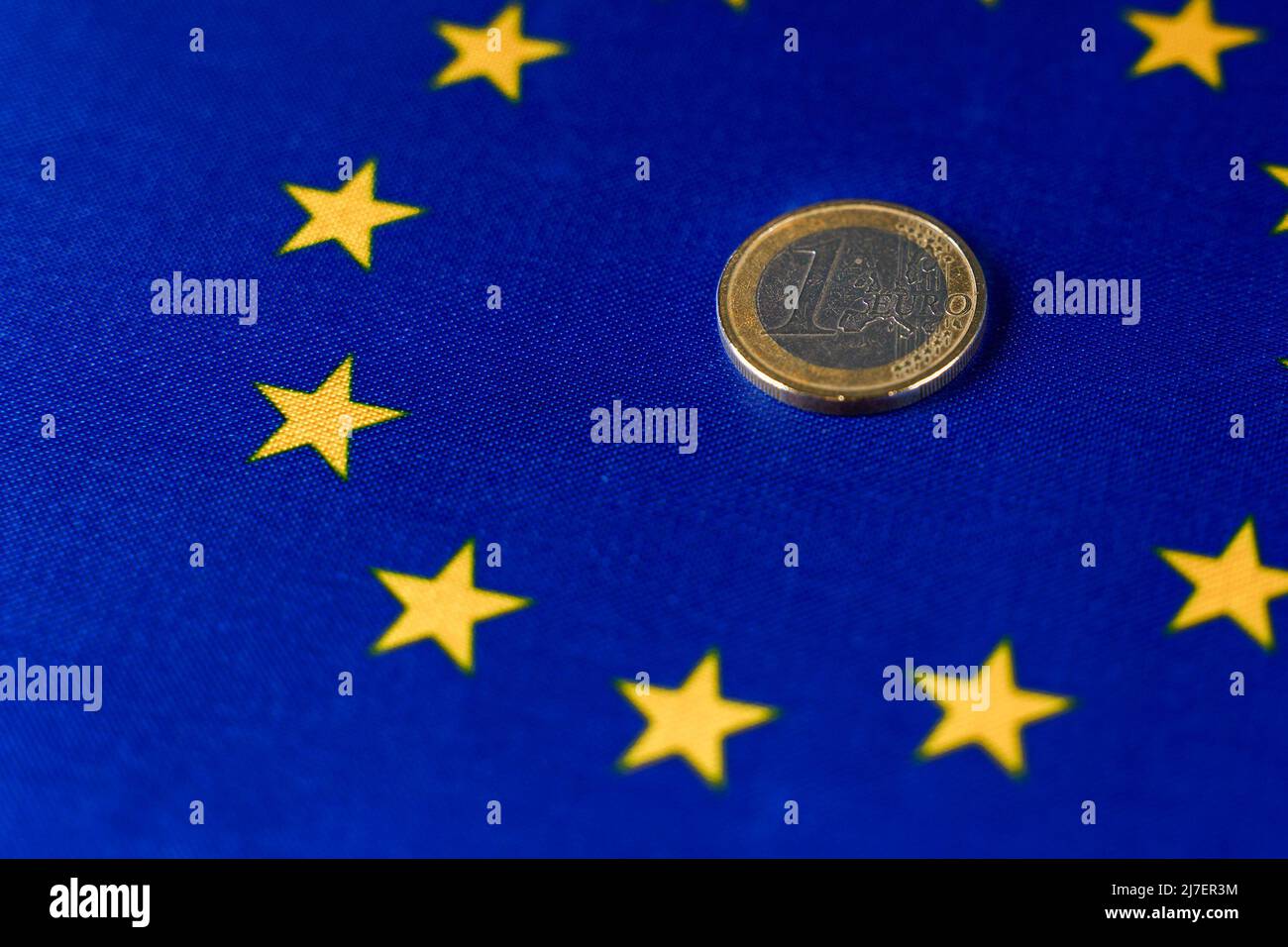Una moneta da euro al centro della bandiera dell'UE. Foto Stock